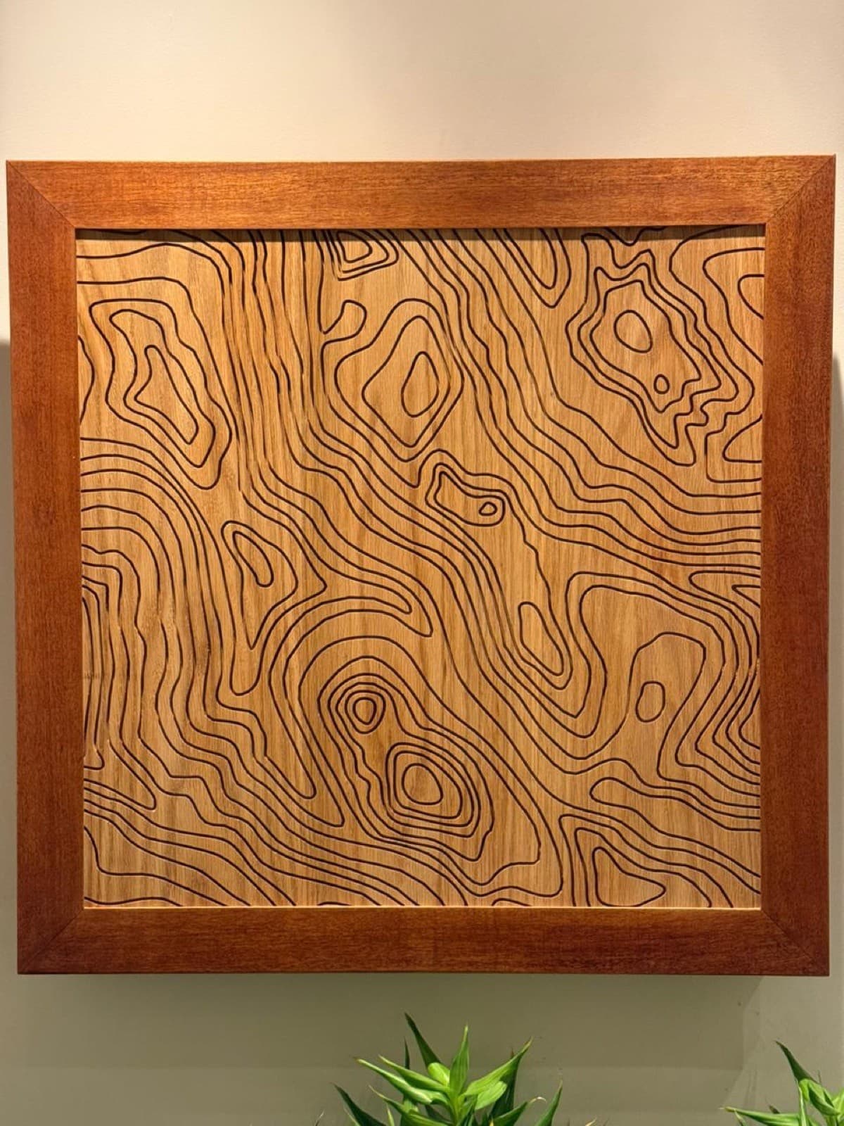 Wood panel carved with topographic contour lines, like a map of the grain